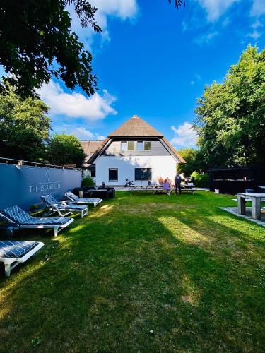 a group of chaise lounges on a lawn in front of a building at The island life Texel - Wellness in De Koog