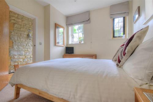 1 dormitorio con 1 cama blanca grande y 2 ventanas en Coram Lodge, en Lyme Regis