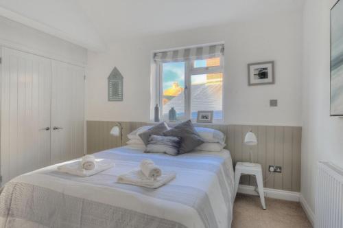 a white bedroom with a bed with towels on it at 11 The Gables in Lyme Regis
