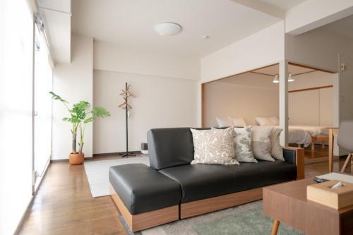a living room with a black leather couch and a table at RIVER WEST Hiroshima 302, 305, 306 - Vacation STAY 54102v in Ōsukachō