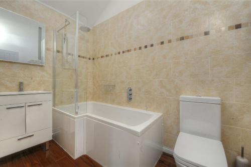 a bathroom with a tub and a sink and a toilet at 11 The Gables in Lyme Regis