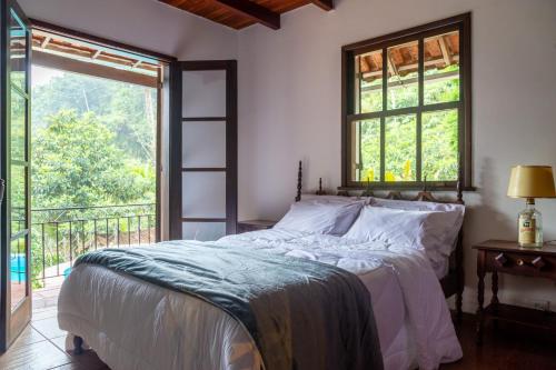 1 dormitorio con cama y ventana grande en CurtaTere piscina lareira pet friendly jardim, en Teresópolis