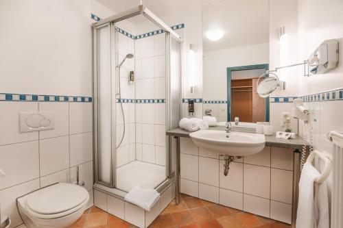 y baño con ducha, aseo y lavamanos. en Hotel am Park en Hückelhoven