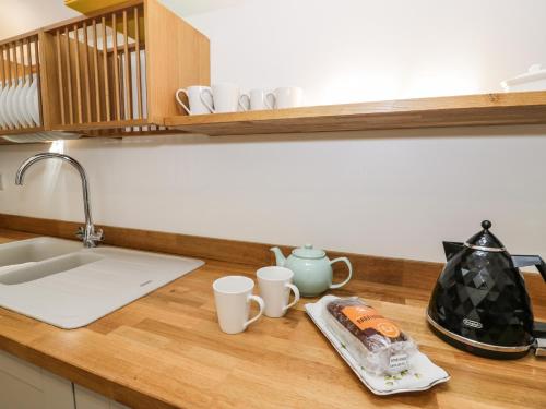 a kitchen counter with a sink and two cups on it at Stabla in Pwllheli