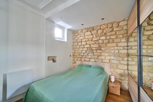 een slaapkamer met een stenen muur en een groen bed bij Comfortable apartment in the heart of Paris - Welkeys in Parijs