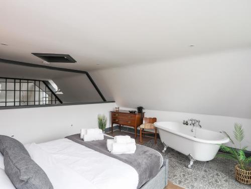 a bedroom with a bed and a bath tub and a sink at The Old School in Conwy