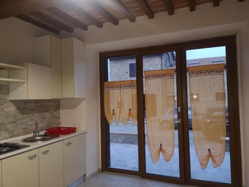 Una cocina con una gran puerta de cristal con ventana. en Villa Castaldo, en Castiglion Fiorentino