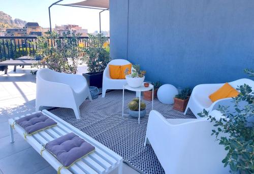 a patio with white chairs and a table on a balcony at Gebel Grin in Palermo