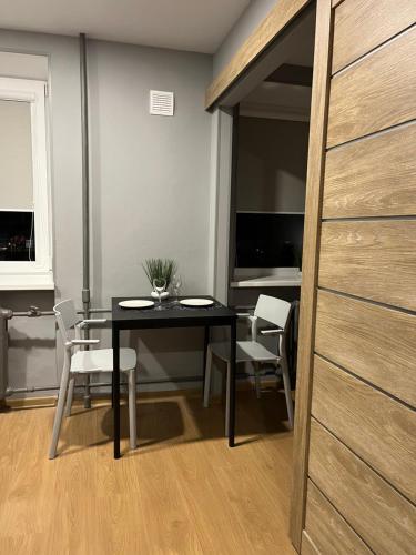 a dining room with a black table and white chairs at Aizkraukle Penthouse apartment in Aizkraukle