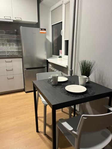 a black table and chairs in a kitchen with a refrigerator at Aizkraukle Penthouse apartment in Aizkraukle