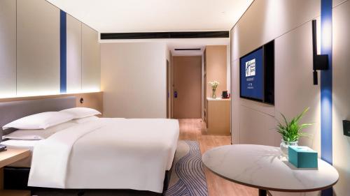 a hotel room with a white bed and a table at Holiday Inn Express Changsha Kaifu by IHG in Changsha