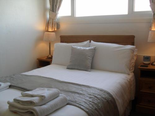 a bedroom with a bed with white sheets and pillows at Invergarry Room Only Guest House For Adults in Windermere