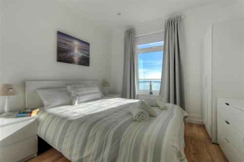 a white bedroom with a bed and a window at 2 Mareeba in Seaton