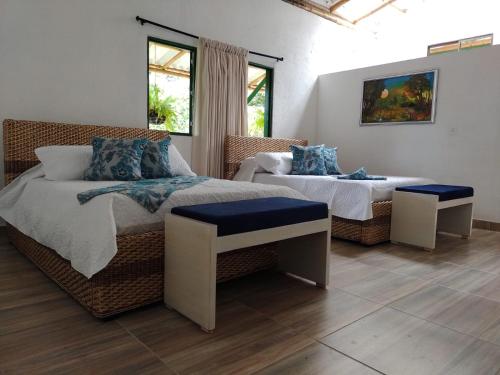 a bedroom with two beds and a couch and windows at Casa Flórez Hotel Campestre in Ibagué