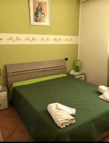 a bedroom with a green bed with two towels on it at appartamento in villa splendente in Castellammare del Golfo