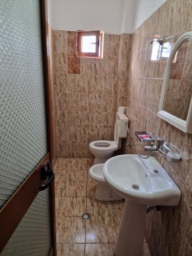 W łazience znajduje się umywalka, toaleta i lustro. w obiekcie Hotel Restaurant Savoja w mieście Pogradec