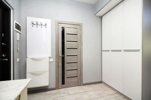 een keuken met witte kasten en een deur bij Прекрасная квартитира в г. Алматы in Alma-Ata