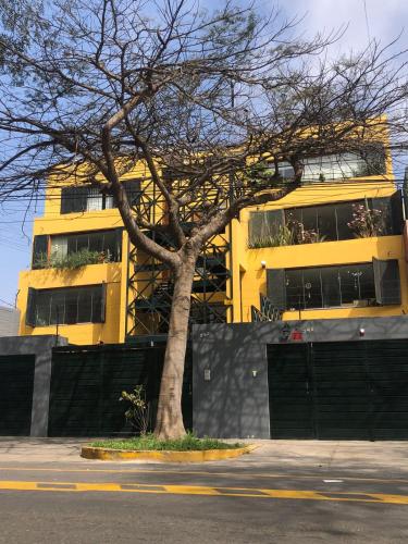 a tree in front of a yellow building at Vistamar Duplex in Lima