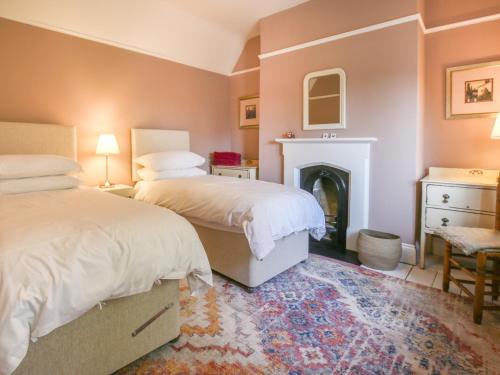 a bedroom with two beds and a fireplace at Gable Lodge in Great Malvern