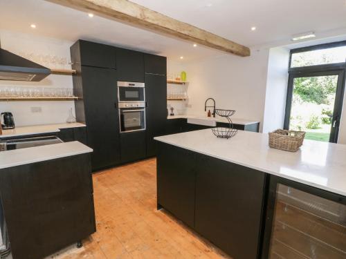 a kitchen with black cabinets and white counter tops at Bodorgan Inn in Bodorgan