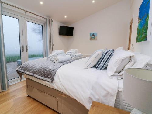 a bedroom with a large white bed with a balcony at 9 Faraway Fields in Liskeard