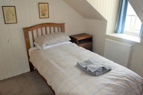 a bedroom with a bed with a blanket and a window at Grooms Cottage in Carsethorn