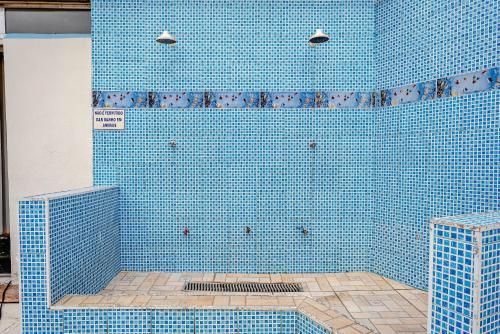 una ducha de azulejos azules con azulejos azules en la pared en APARTAMENTO, ATÉ 4 PESSOAS,20 Metros da PRAIA do SONHO, PÉ NA AREIA,100 MB WI-FI, en Itanhaém