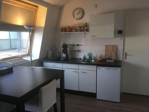 a kitchen with white cabinets and a clock on the wall at Studio, 21 minutes by bus to downtown Amsterdam in Purmerend