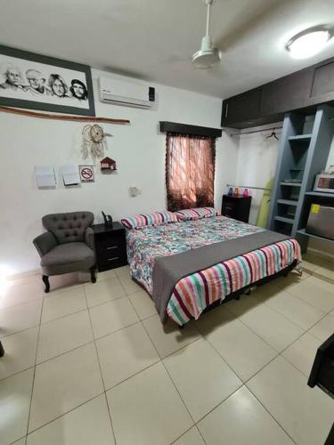 a bedroom with a bed and a chair in it at Departamento independiente con todos lo servicios in Chetumal