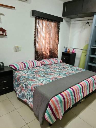 a bedroom with a bed with a comforter and a window at Departamento independiente con todos lo servicios in Chetumal