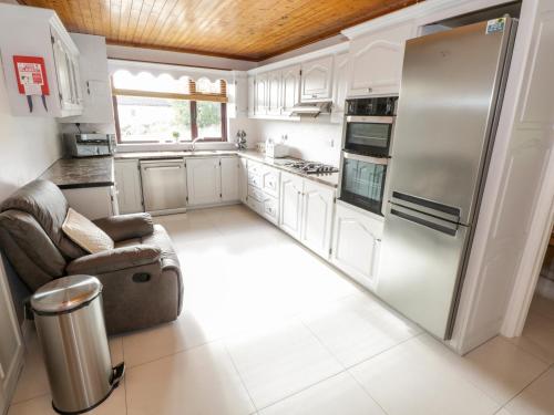a kitchen with white cabinets and a stainless steel refrigerator at Aras Iosgan in Carraroe