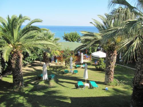 a resort yard with chairs and palm trees and the ocean at Levantino Studios & Apartments in Vasilikos