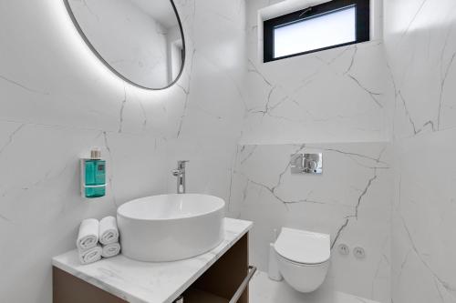 a white bathroom with a sink and a mirror at Kuk Oaza Luxury Villas in Makarska