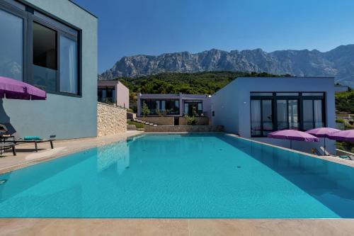 a swimming pool in a villa with mountains in the background at Kuk Oaza Luxury Villas in Makarska