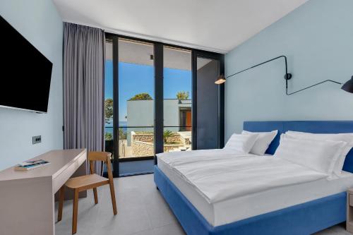 a bedroom with a bed and a desk and a television at Kuk Oaza Luxury Villas in Makarska