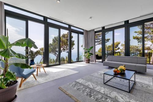 a living room filled with furniture and large windows at Kuk Oaza Luxury Villas in Makarska