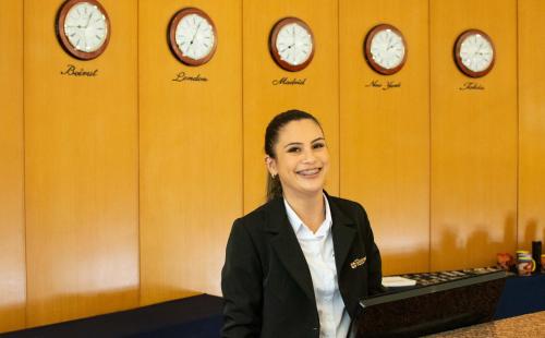 a woman in a room with clocks on the wall at Hotel Golden Park Internacional Foz & Convenções By Nacional Inn in Foz do Iguaçu