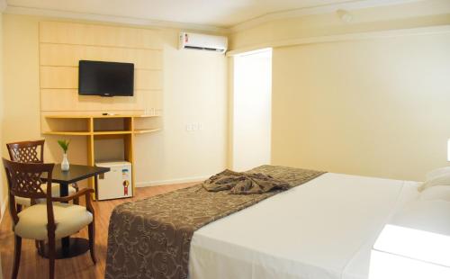 a bedroom with a bed and a desk and a television at Hotel Golden Park Internacional Foz & Convenções By Nacional Inn in Foz do Iguaçu