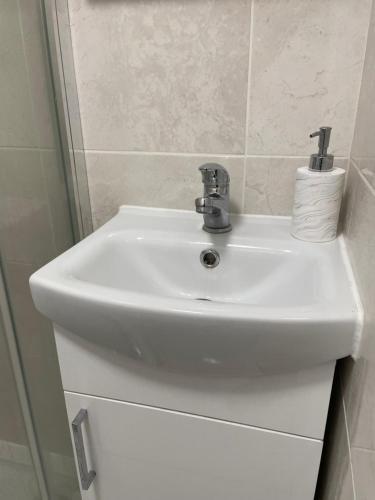 a white bathroom sink with a roll of toilet paper at The Mews in Erith