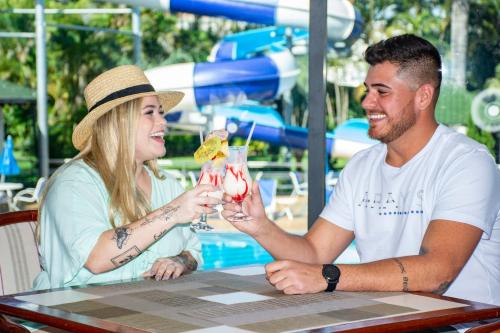 a man and a woman sitting at a table with drinks at Hotel Golden Park Internacional Foz & Convenções By Nacional Inn in Foz do Iguaçu