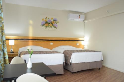 a hotel room with two beds and a table at Hotel Golden Park Internacional Foz & Convenções By Nacional Inn in Foz do Iguaçu