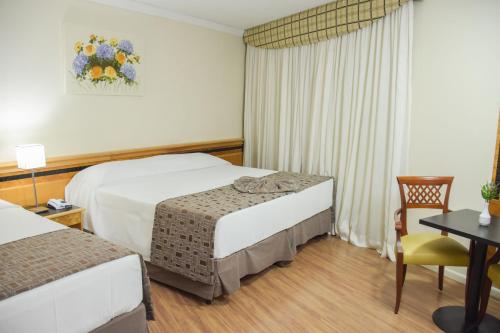 a hotel room with two beds and a table at Hotel Golden Park Internacional Foz & Convenções By Nacional Inn in Foz do Iguaçu