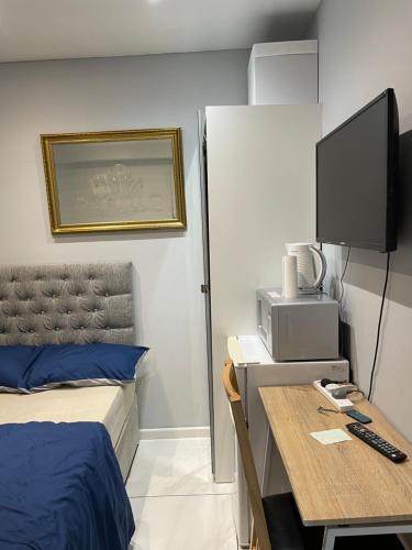 a bedroom with a bed and a desk with a television at The Mews in Erith