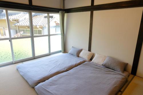 Bett in einem Zimmer mit einem großen Fenster in der Unterkunft Private inn Mei Vacation Rental MEI - Vacation STAY 57858v in Ino