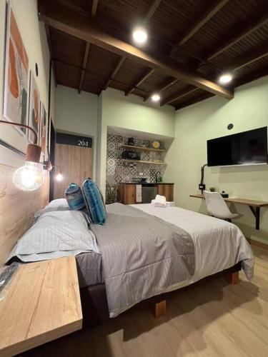a bedroom with a large bed and a desk at Inmueble cerca al estadio NID204 By Roots Rentals in Medellín