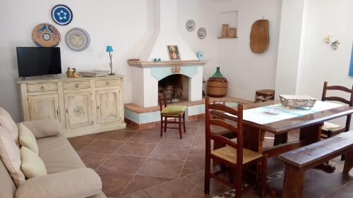 een woonkamer met een tafel en een open haard bij Casa di Campagna in Galtellì