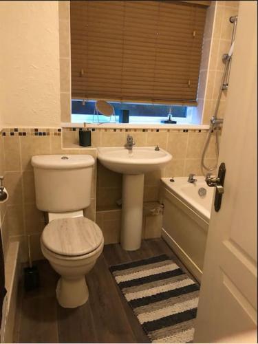 een badkamer met een toilet, een wastafel en een bad bij Lovely one-bed condo with free parking on premises in Sunderland