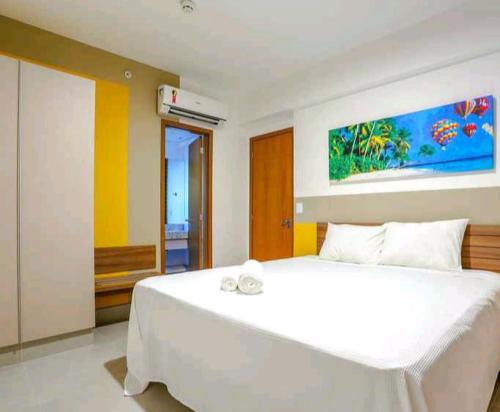 a bedroom with a white bed and a painting on the wall at Olímpia Park Resort-frente Thermas Laranjais-apt 5 p in Olímpia