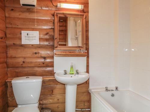 a bathroom with a toilet and a sink and a tub at Otter Lodge in Strathpeffer