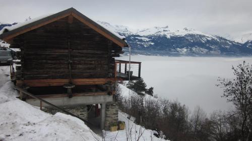 a log cabin in the snow next to a lake at Studio Raccard Cendré in Grône